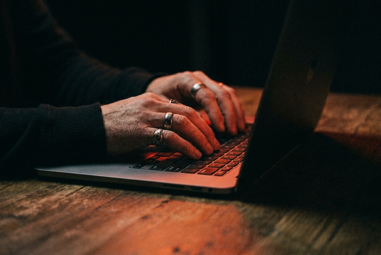 Close-up of an operator's hands building an agent on a laptop, lit by the warm glow of the screen